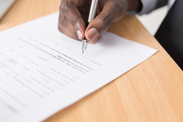 A hand signs a paper for Medicare insurance.